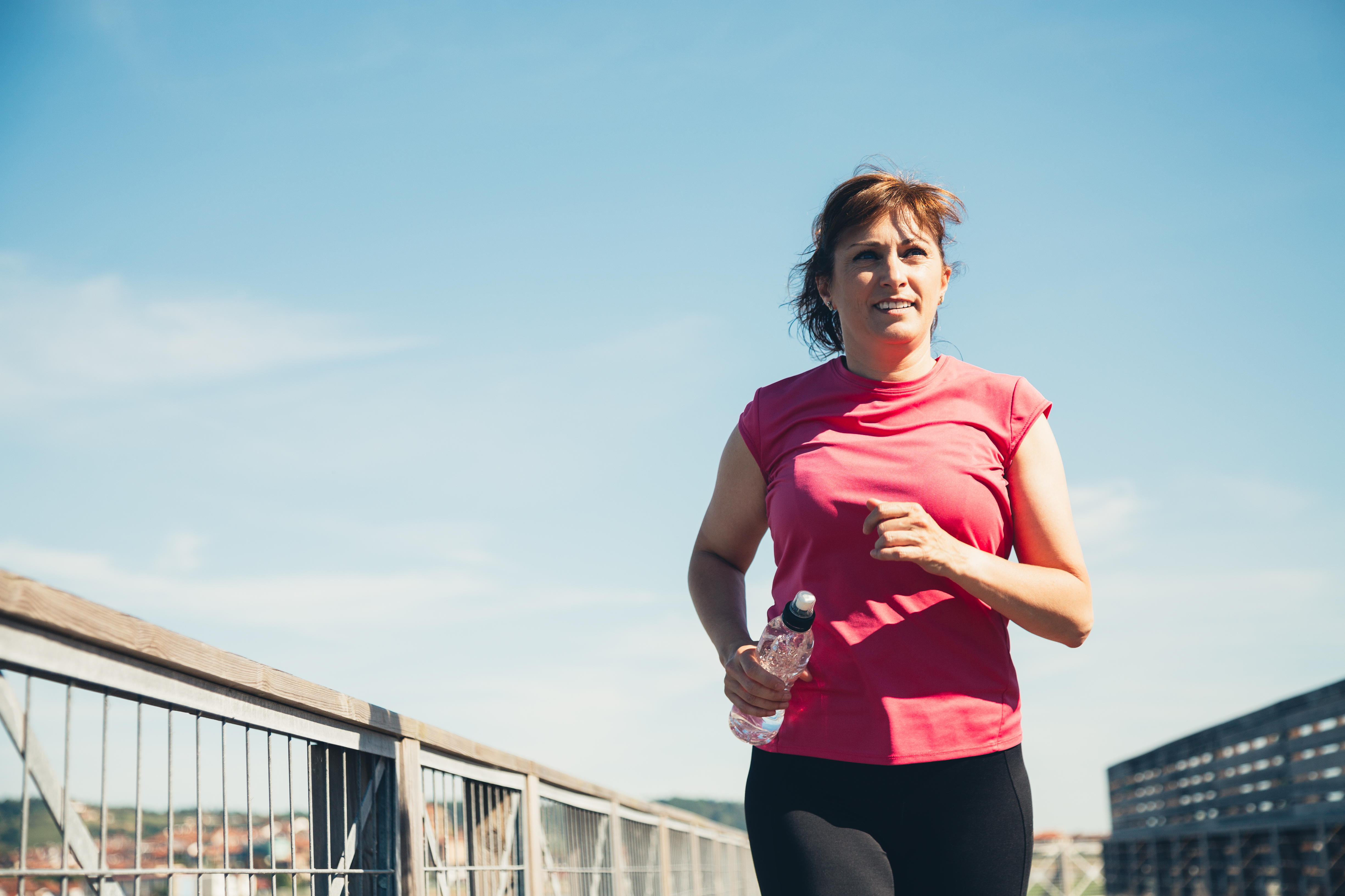 Middle aged woman running with water bottle