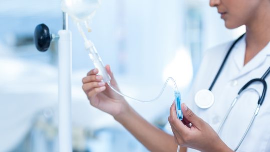 Nurse connecting an intravenous drip in hospital room